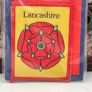 May include: A yellow patch with a red embroidered rose and the text "Lancashire" in black.