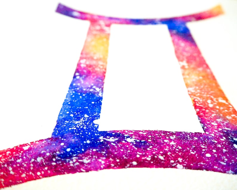 Puede incluir: Una pintura de acuarela del signo del zod&iacute;aco G&eacute;minis. El signo est&aacute; delineado en un dise&ntilde;o vibrante y multicolor con salpicaduras de pintura blanca.