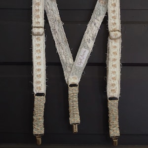 Puede incluir: Tirantes con estampado blanco y verde con clips de metal dorado. Los tirantes tienen una etiqueta que dice "Good Jeans".