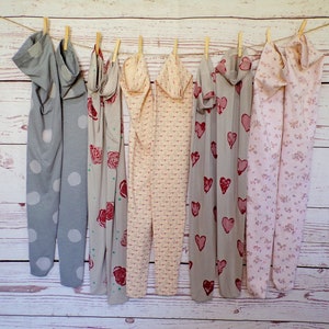 May include: Seven pairs of patterned tights hanging on a clothesline. The tights are in various colors and patterns, including polka dots, roses, hearts, and floral designs.