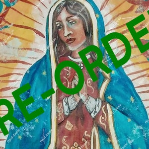 May include: An artistic painting of a religious figure, featuring a woman in a blue cloak adorned with gold stars. The artwork has a warm color palette with a halo effect and the text "PRE-ORDER" in green.