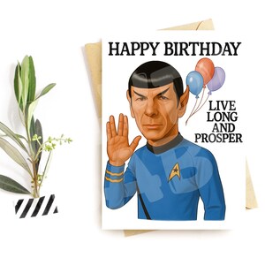 Puede incluir: Una tarjeta de cumpleaños con una ilustración de dibujos animados de un personaje con uniforme azul, con las palabras "Happy Birthday" en la parte superior. La tarjeta también incluye la frase "Live Long and Prosper" y tres globos.