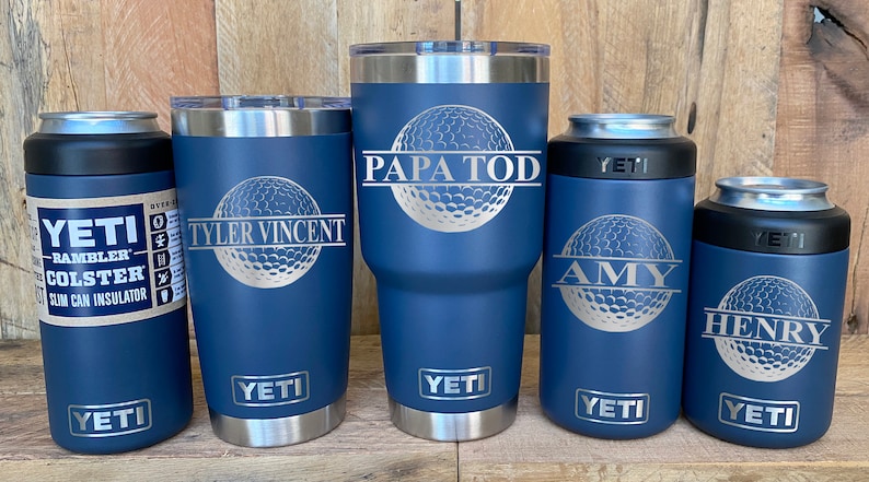 May include: Five Yeti tumblers with personalized names and a golf ball design. The tumblers are in various sizes and are all blue with silver accents.