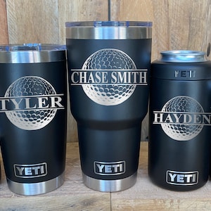 May include: Five black Yeti tumblers with silver lids and a golf ball design. The tumblers are personalized with the names "Chase Smith", "Tyler", "Hayden", and "Higgins".