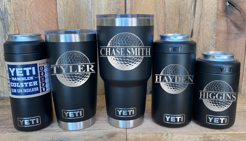 May include: Five black Yeti tumblers with silver lids and a golf ball design. The tumblers are personalized with the names "Chase Smith", "Tyler", "Hayden", and "Higgins".