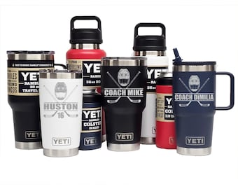 May include: A collection of YETI Rambler drinkware in various sizes and colors, including tumblers, bottles, and can insulators. Several items feature custom laser-engraved hockey-themed graphics with names like Coach Mike, Coach Dimilia, and Huston 16.