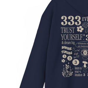 May include: Navy blue hoodie with a white graphic print featuring the text "333 EVE TRUST YOURSELF & dream big DIVINE TIMING 333 listen to your intuition 3" with mushroom and flower illustrations.
