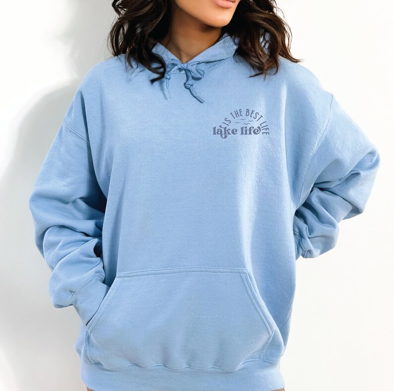 Puede incluir: Sudadera azul claro con capucha y cord&oacute;n ajustable, y bolsillo delantero. El texto "is the best lake life" est&aacute; impreso en azul m&aacute;s oscuro en el pecho. La sudadera es de material suave.