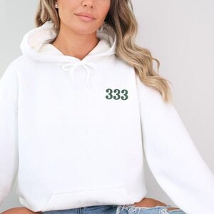 May include: White hooded sweatshirt with a green 333 embroidered on the front.