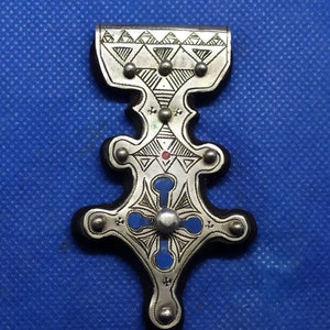 May include: A silver pendant with a blue and red enamel design. The pendant is in the shape of a cross with a decorative top.