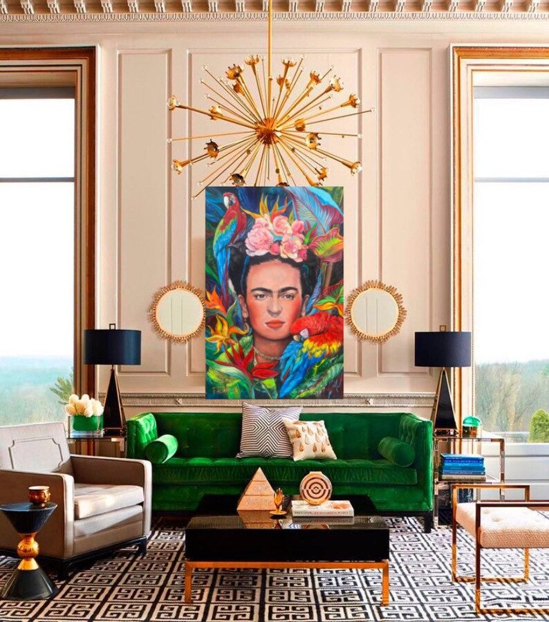 Pu&ograve; includere: Un divano in velluto verde con bordi dorati si trova in un soggiorno con un tappeto a motivi bianco e nero. Un dipinto di Frida Kahlo con pappagalli e fiori &egrave; appeso al muro sopra il divano. La stanza &egrave; decorata con accenti dorati e un grande lampadario dorato.