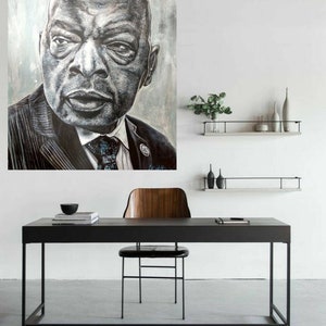 以下が含まれることがあります： スーツとネクタイを着た男性の白黒の肖像画。絵は、黒い机と木製の椅子の上にある白い壁にかけられています。