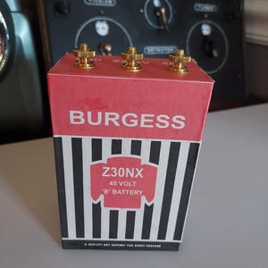 May include: A vintage Burgess Z30NX 45-volt 'B' battery. The red top features the brand name and gold-colored terminals. The lower section has black and white vertical stripes. The text "A QUALITY DRY BATTERY FOR EVERY PURPOSE" is printed at the bottom.