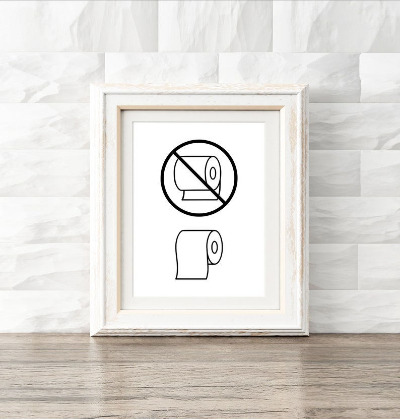 May include: A white framed print with a black and white illustration of a toilet paper roll with a red circle and diagonal line through it. Below the circle is a black and white illustration of a toilet paper roll.