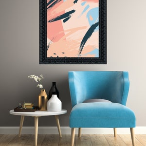 May include: A blue armchair with a black framed abstract painting with pink, blue, and black brushstrokes hanging above it. The armchair is in front of a white table with a gold vase and two white vases with flowers.