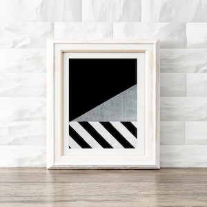 Könnte beinhalten: Ein weiß gerahmtes Bild mit einem geometrischen Design in Schwarzweiß. Das Design zeigt ein schwarzes Dreieck mit einem weißen Streifenmuster am unteren Rand.