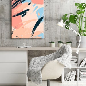 May include: Abstract art print featuring pink, blue, and black brushstrokes on a white background. The print is hanging on a grey wall above a white desk with a white chair and a bookshelf.