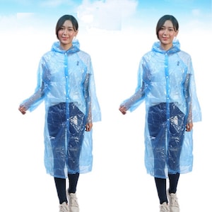 May include: Two people wearing light blue disposable plastic raincoats with hoods. The raincoats are transparent and have a button closure.