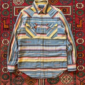 Op de afbeelding: Een overhemd met lange mouwen en een gestreept patroon in blauw, geel, rood en paars. Het overhemd heeft twee borstzakken en een kraag. Het Polo Ralph Lauren-logo is zichtbaar op de kraag.