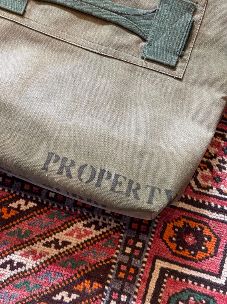 May include: A white ceramic mug with a black handle and the text "But First, Coffee" in a bold, black font. The mug is set against a blurred background, suggesting a cozy setting.