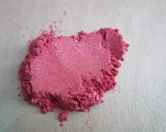May include: A close-up of a pile of pink mica powder. The powder has a fine, shimmery texture.