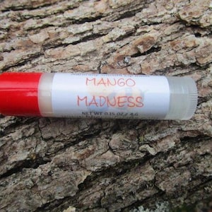 May include: A red and clear lip balm tube with a white label that reads "Mango Madness" and "Net Wt 0.15 oz / 4.6 g".