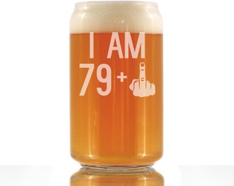 May include: A clear glass beer can with a white foam head. The can has the text "I AM 79+" and a middle finger emoji etched on the side.