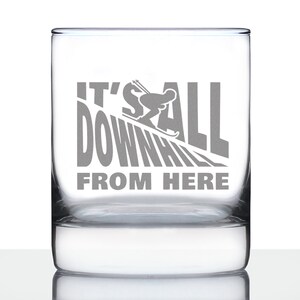May include: A clear glass tumbler with a grey etched design of a skier going downhill with the text "It's all downhill from here".