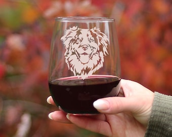 Könnte beinhalten: Ein klares, stielloses Weinglas mit einem gravierten Design eines Australian Shepherd-Hunde-Kopfes. Das Glas ist mit Rotwein gefüllt.