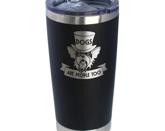Op de afbeelding: Zwarte reistumbler van roestvrij staal met een zilveren deksel. De tumbler heeft een lasergegraveerd ontwerp van een hond met een hoge hoed en bril met de tekst "Honden zijn ook mensen".