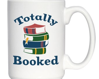 May include: White ceramic coffee mug with a blue and red graphic of a stack of books and the text "Totally Booked".