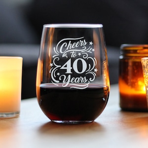 May include: A clear glass wine glass with the text "Cheers to 40 Years" etched on the side. The glass is filled with red wine.