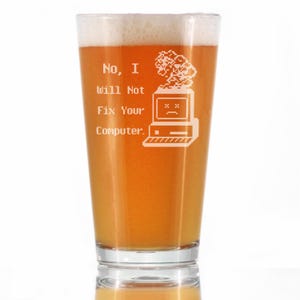 May include: A pint glass filled with beer and foam. The glass has the text "No, I Will Not Fix Your Computer." and a graphic of a retro computer etched on the front. The beer is a golden amber color.
