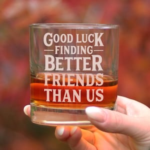 Könnte beinhalten: Ein durchsichtiger Glasbecher mit dem Text "Good Luck Finding Better Friends Than Us" auf der Seite. Der Becher ist mit einer braunen Flüssigkeit gefüllt und wird von einer Hand gehalten.