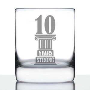 May include: A clear glass tumbler with an etched design of a column with the number 10 and the text "Years Strong".