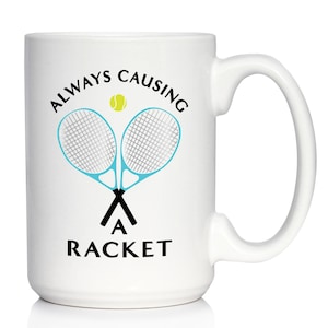 May include: White ceramic coffee mug with a black and blue tennis racket design and the text "ALWAYS CAUSING A RACKET".