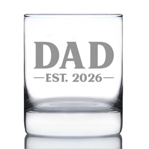 Puede incluir: Un vaso transparente de forma cuadrada con la palabra "DAD" en letras grises. Debajo de la palabra "DAD" está el texto "-EST. 2026-" en gris. El vaso está vacío y se encuentra sobre una superficie blanca.