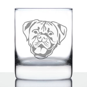 Puede incluir: Un vaso de vidrio transparente con un diseño grabado de la cabeza de un bulldog. El bulldog está mirando hacia adelante con la boca cerrada y las orejas levantadas.