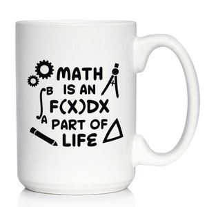 Puede incluir: Taza de café de cerámica blanca con un diseño negro que dice "Las matemáticas son una parte integral de la vida" con símbolos matemáticos como una brújula, un lápiz y engranajes.