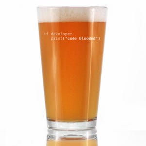 May include: A pint glass filled with beer, topped with a foamy head. The glass has the text "if developer: print("code blooded")" printed on it. The beer is a light amber colour.