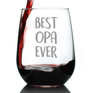 May include: A clear glass wine glass with the text "BEST OPA EVER" printed on it. Red wine is being poured into the glass.