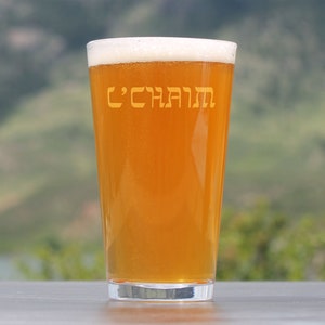 May include: A glass of amber-colored beer in a pint glass with the Hebrew words "L'Chaim" etched on the side.
