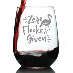 May include: A clear stemless wine glass with the text "Zero Flocks Given" and a silhouette of a flamingo. The glass is filled with red wine.