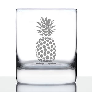 May include: A clear glass tumbler with a white pineapple design etched on the front. The pineapple is a simple silhouette with a detailed pattern of scales.