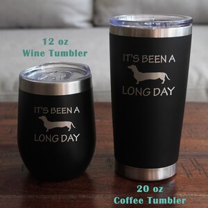 May include: Two stainless steel tumblers with black powder coating. The smaller tumbler is 12 ounces and says "It's been a long day" with a dachshund silhouette. The larger tumbler is 20 ounces and says "It's been a long day" with a dachshund silhouette.
