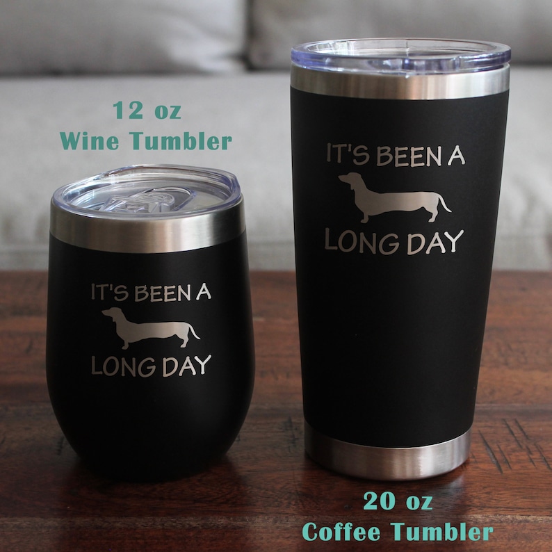 May include: Two stainless steel tumblers with black powder coating. The smaller tumbler is 12 ounces and says "It's been a long day" with a dachshund silhouette. The larger tumbler is 20 ounces and says "It's been a long day" with a dachshund silhouette.