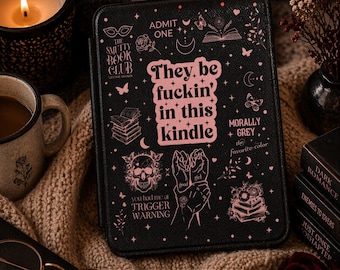 May include: A black Kindle e-reader case featuring pink graphic illustrations of a skull, books, butterflies, and hands. The text reads: They be fuckin' in this kindle, The Smutty Book Club, Admit One, Morally Grey, and Trigger Warning.