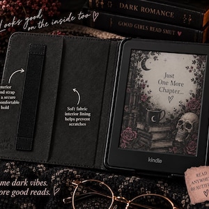 May include: A black e-reader case with a soft interior lining and an elastic hand strap. The e-reader screen displays a graphic with a skull, books, a mug, and the text Just One More Chapter. The case features the brand name Wicked Petal.