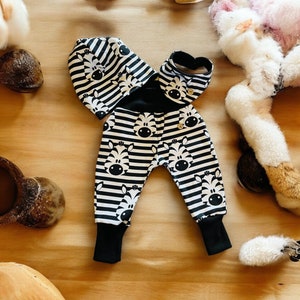 Könnte beinhalten: Schwarz-weiß gestreifte Babyhose mit Zebra-Muster und einer passenden schwarz-weiß gestreiften Mütze.
