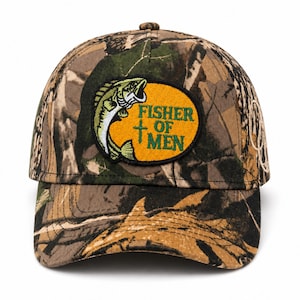 May include: A camouflage baseball cap featuring an oval patch on the front. The patch displays a green fish illustration and the text "FISHER OF MEN" with a cross symbol in yellow and green embroidery against a solid yellow background.